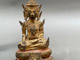a gold statue of a buddha sitting on top of a table