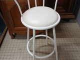 a white bar stool with a white seat on a tiled floor