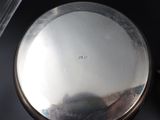 a silver pocket watch sitting on a table next to a cup