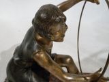 une statue en bronze d'un garçon avec un arc et des flèches