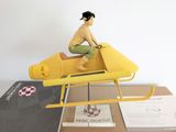 a figurine of a woman sitting on top of a yellow helicopter