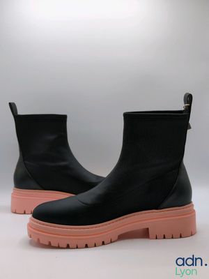 un gros plan sur une paire de bottes noires à semelles roses