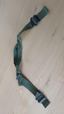 une ceinture vert olive avec une boucle en métal posée sur une surface en bois