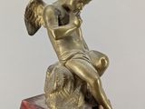 bronze statue of a child sitting on a rock with a bird on it
