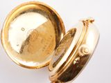 a close up of a gold pocket watch on a white surface