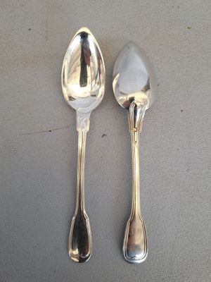 deux cuillères en argent posées sur une table l'une à côté de l'autre