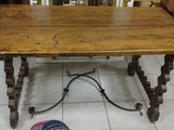 a wooden table with a metal base on a tile floor
