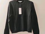 un pull noir suspendu à un cintre accroché au mur