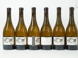 six bouteilles de vin sont alignées sur une surface blanche