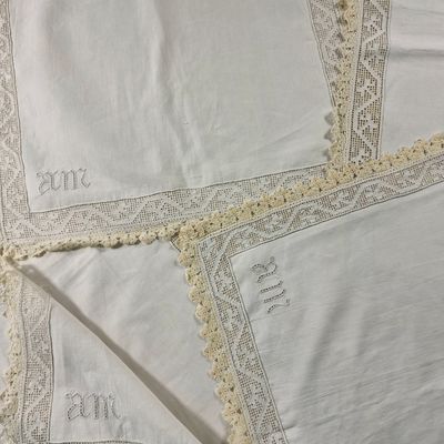 plusieurs pièces de linge blanc ornées de dentelle, posées sur un lit