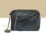 a black quilted bag with a chain strap on a white surface