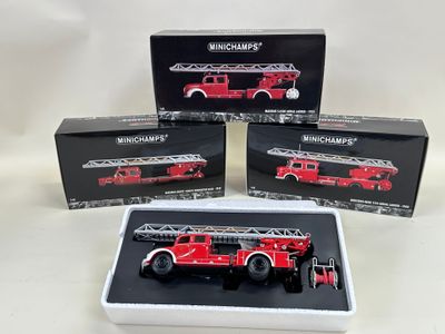 trois camions de pompiers rouges se trouvent dans un carré blanc posé sur une surface blanche
