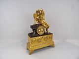 a gold clock with an angel sitting on top of it