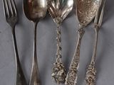 four silver spoons and a fork are lined up on a table
