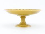 a yellow bowl on a pedestal on a white background