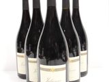 six bottles of wine are lined up in a row on a white surface