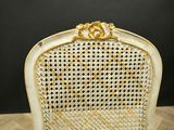 a white chair with gold trim and a wooden seat on a wooden table
