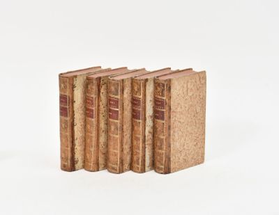 cinq vieux livres sont alignés sur une surface blanche
