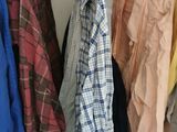 many shirts hanging on a rack in a closet