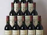 bottles of red wine sit on a wooden table in front of a white wall