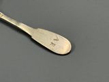 une cuillère en argent avec un manche en argent posée sur une table