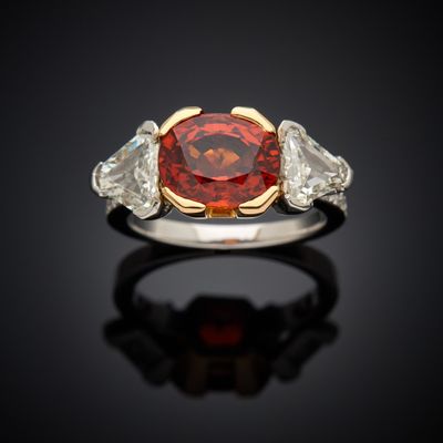 a red diamond and diamond ring with two white diamonds on a black surface