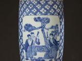 a blue and white vase on a table with a lamp on it