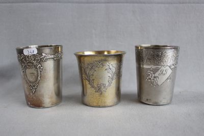three silver cups with designs on them sitting on a table