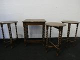 trois tables en bois aux pieds tournés, posées sur un tapis noir