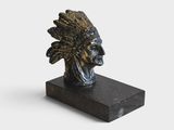 une statue représentant une tête d'Indien posée sur un socle en marbre noir