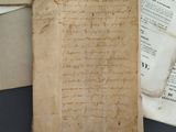an old book with writing on it sitting next to a pile of papers