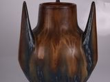 un vase marron et noir posé sur une table, sur fond blanc