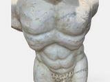 a statue of a male torso on display on a white surface