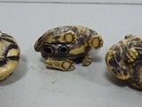 three small carved animal heads are sitting on a white surface