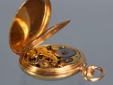 a gold pocket watch sitting on a reflective surface