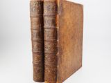two old books sitting on top of each other on a white surface