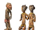 trois figurines en bois représentant des personnes debout les unes à côté des autres sur une surface blanche