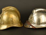 pair of silver and gold fire helmets on a black background