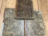 two old books sitting on top of a wooden floor next to each other