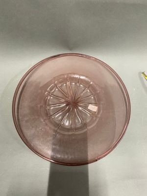 a pink glass bowl sitting on a table next to a toothbrush