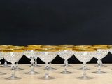 eight crystal wine glasses with gold rims on a wooden table