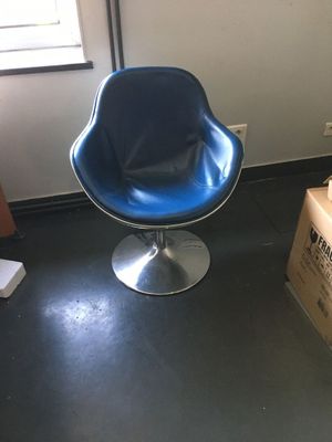 a blue chair sitting in a room with boxes on the floor