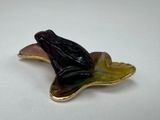 a frog that is sitting on a leaf shaped brooch
