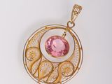 un gros plan sur un pendentif en or orné d'une pierre rose