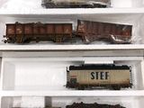 trois wagons de train miniature dans des boîtes en plastique, posés sur une table