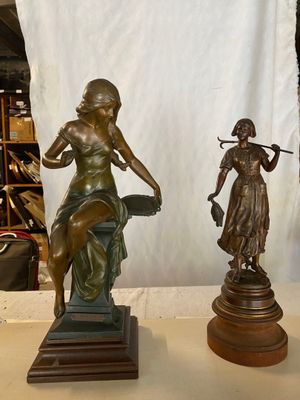 deux statues représentant une femme et un homme assis sur un banc