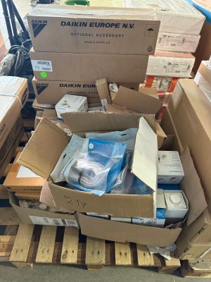 Des cartons contenant du matériel électronique sont empilés sur une palette dans un entrepôt