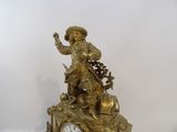 a gold clock with a statue of a man riding a horse