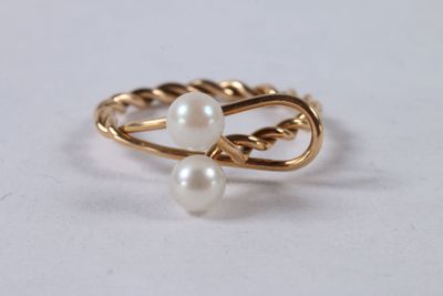 Gros plan sur une bague en or ornée de deux perles