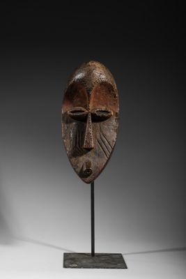 un masque en bois posé sur un socle